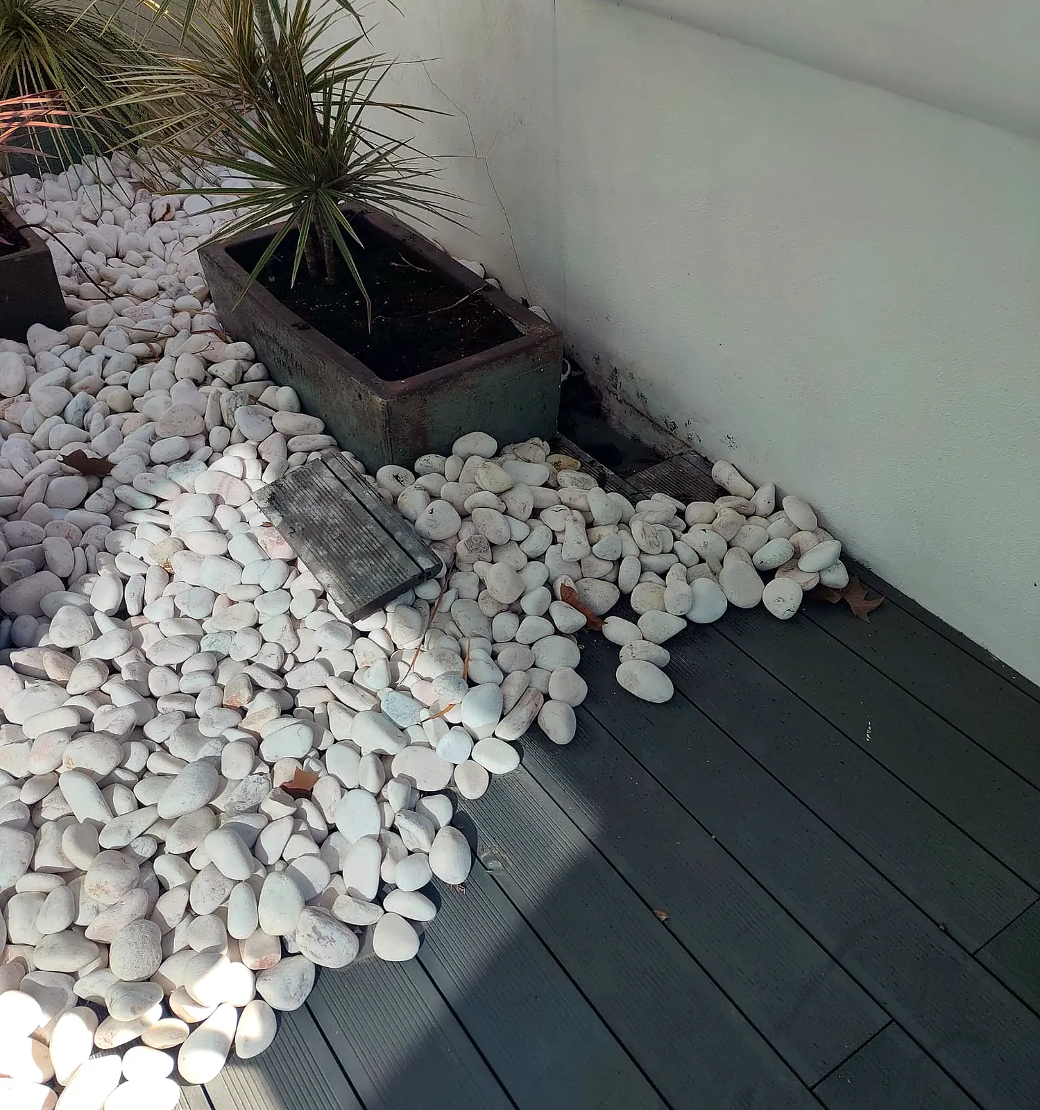 Terraço concluído com deck compósito, floreira e seixo branco